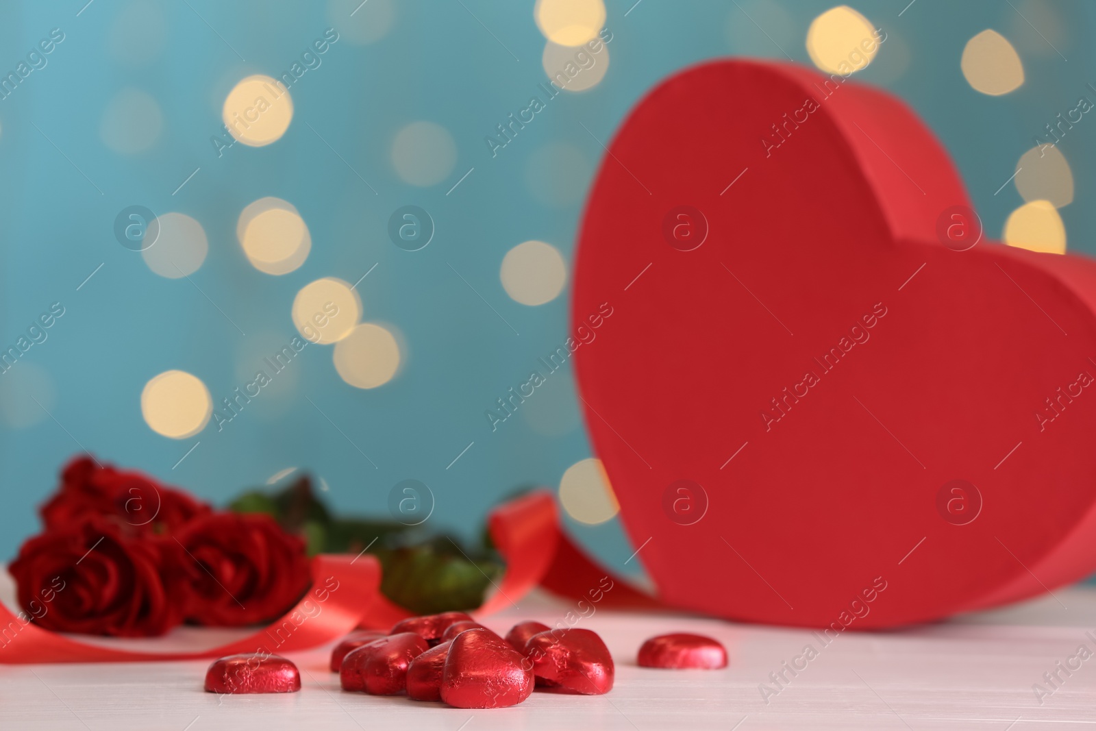 Photo of Heart shaped chocolate candies on pink table against blurred lights. Valentines's day celebration