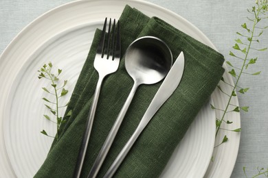 Stylish setting with cutlery, leaves and plates on grey table, top view