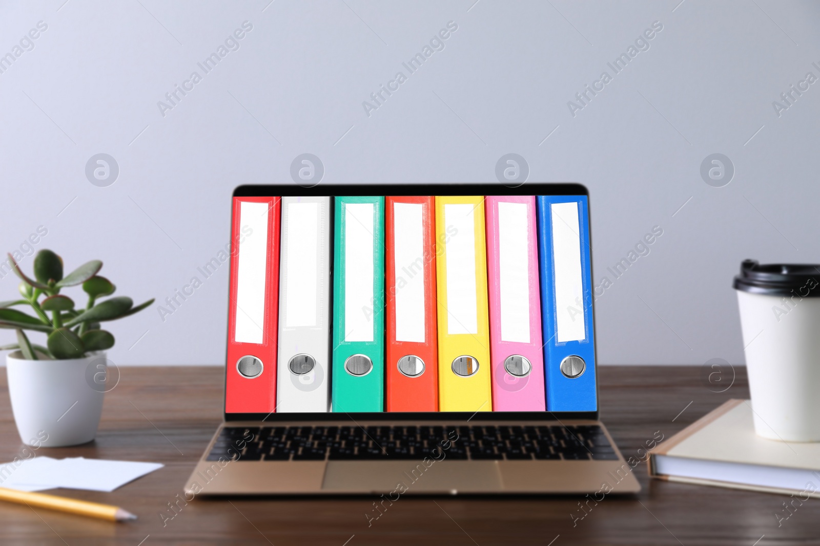 Image of Store and organize information. Modern laptop with hardcover office folders on screen