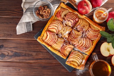 Photo of Freshly baked apple pie served with tea on wooden table, flat lay. Space for text