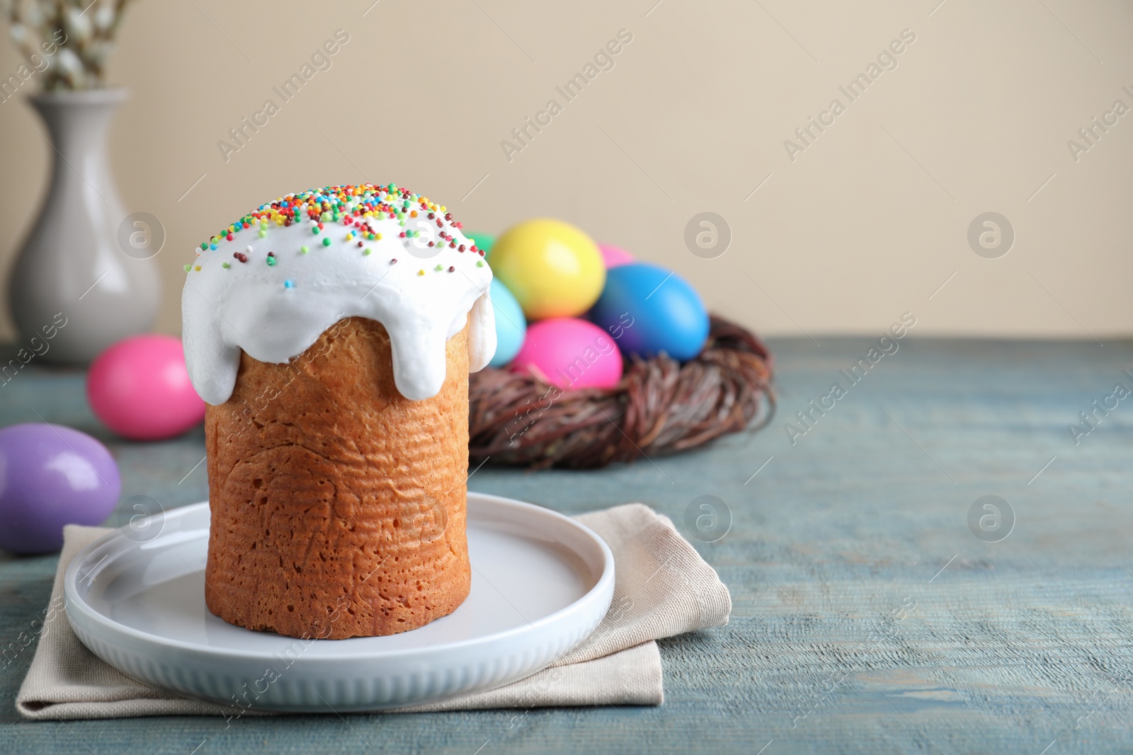 Photo of Easter cake and colorful eggs on blue wooden table, space for text