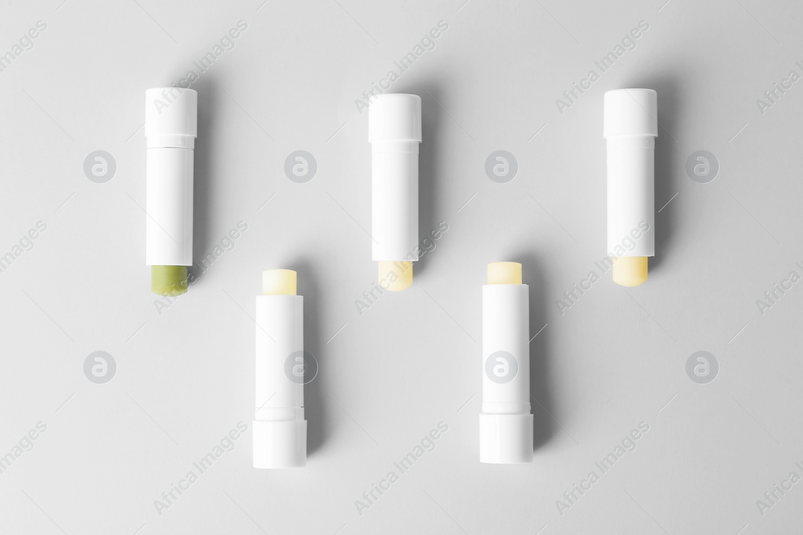 Photo of Flat lay composition with hygienic lipsticks on grey background