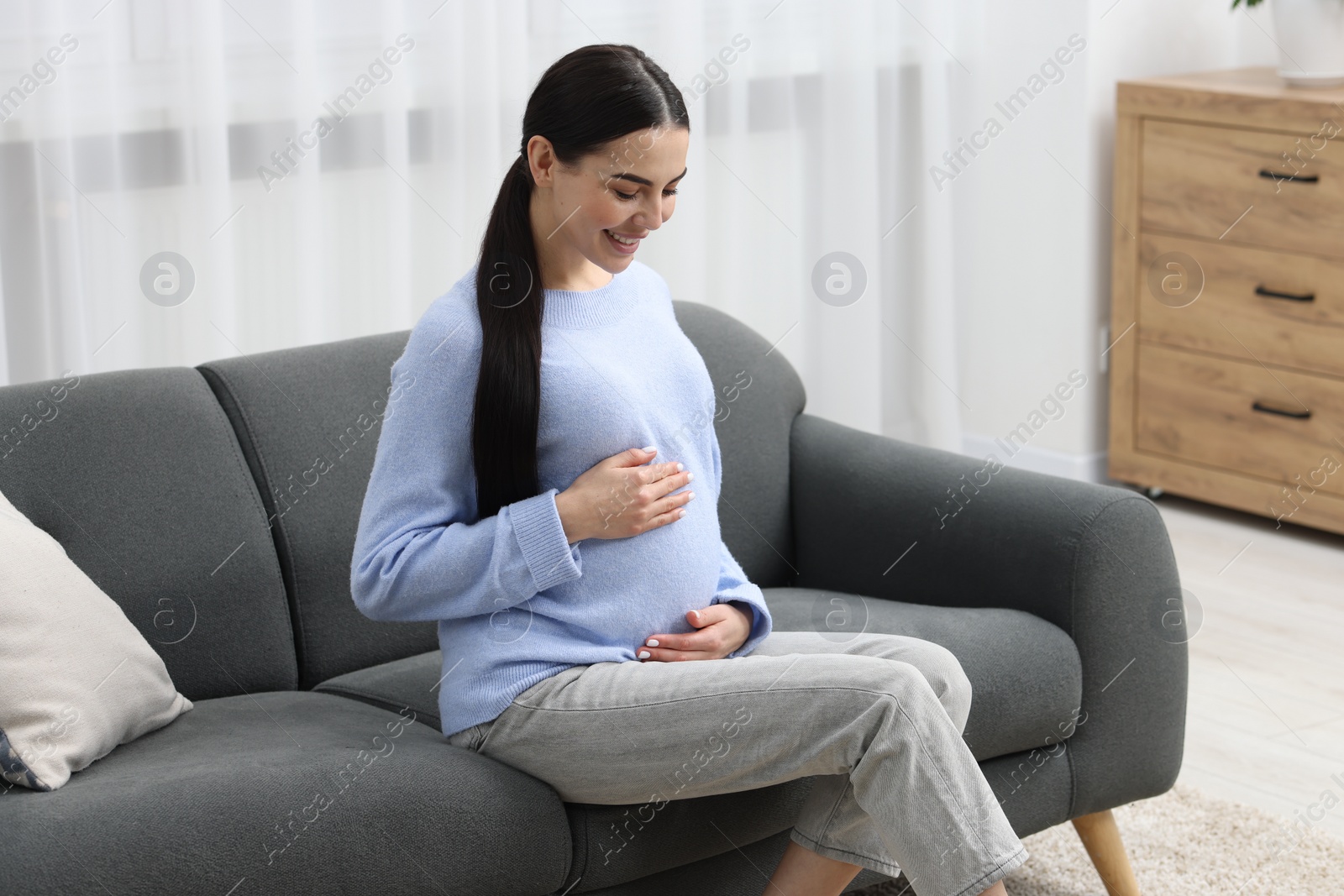 Photo of Happy pregnant woman on sofa at home