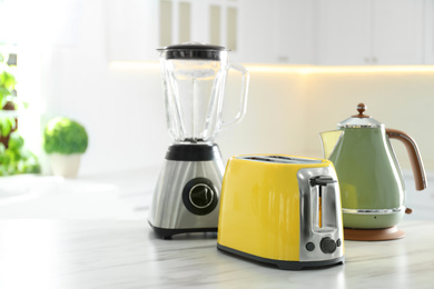 Photo of Set of modern home appliances on white marble table in kitchen