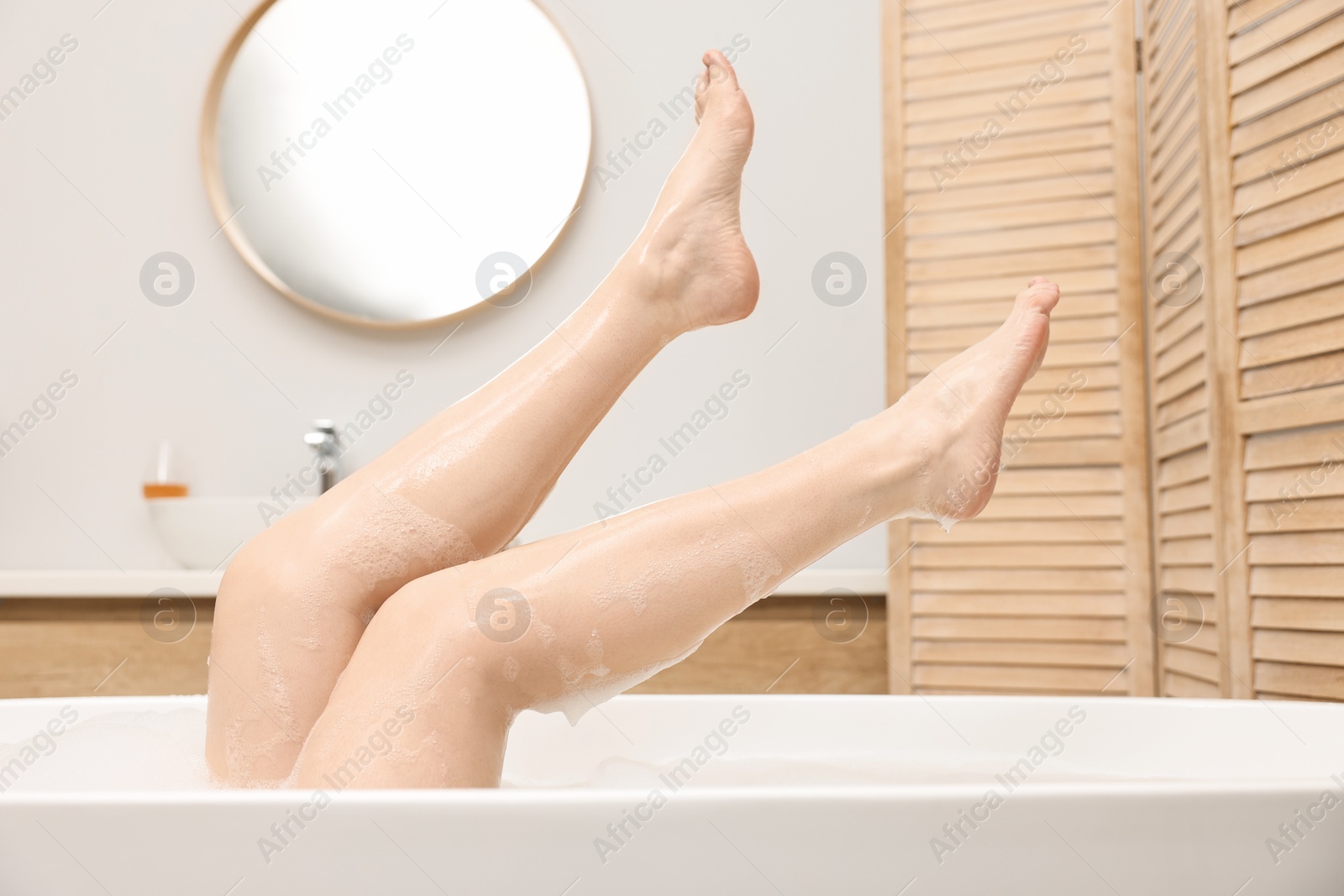 Photo of Woman taking bath with foam in tub indoors, closeup