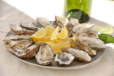 Photo of Fresh oysters with cut juicy lemon served on table