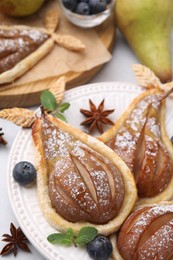 Delicious pears baked in puff pastry with powdered sugar served on table, closeup