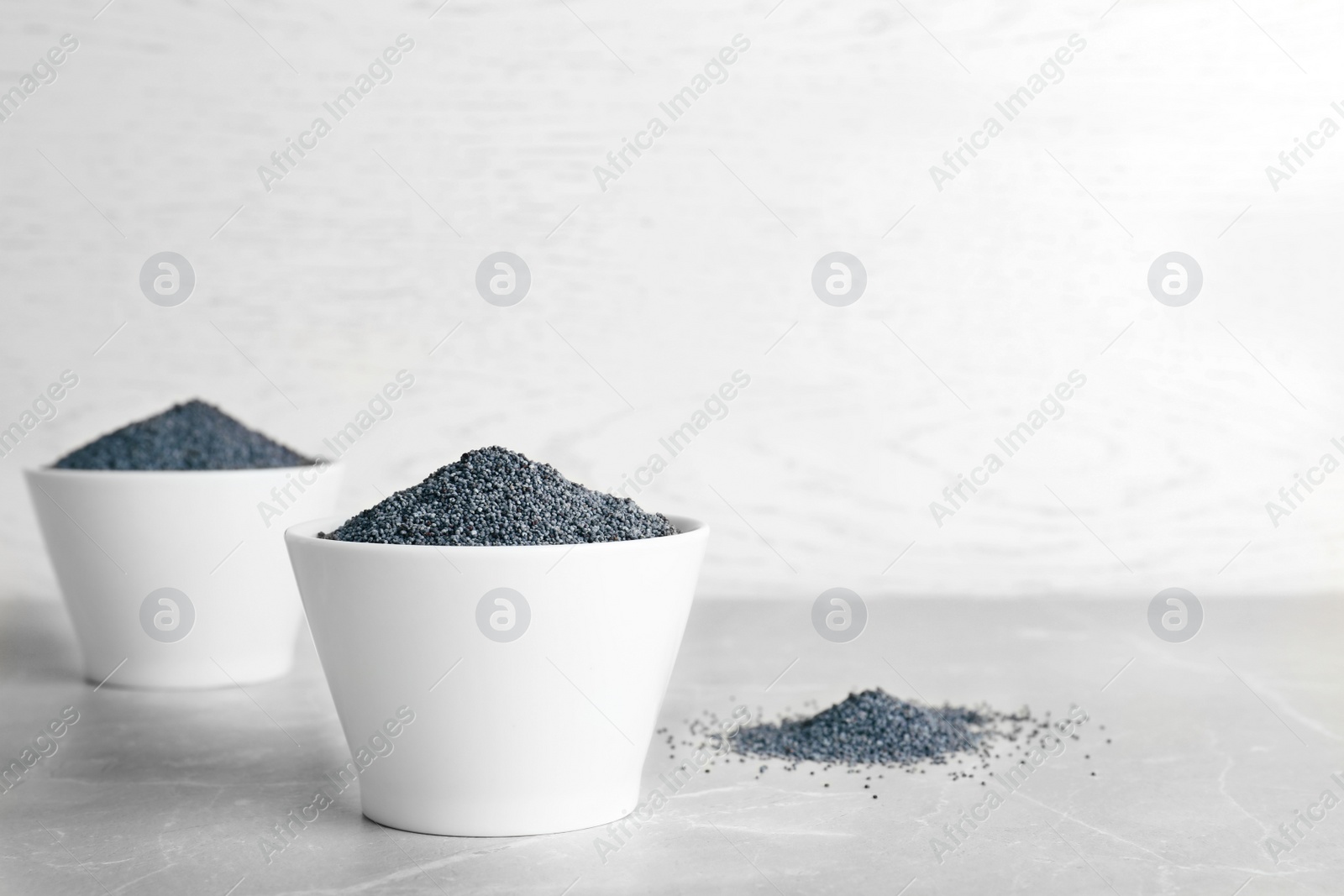 Photo of Poppy seeds in bowl on table. Space for text