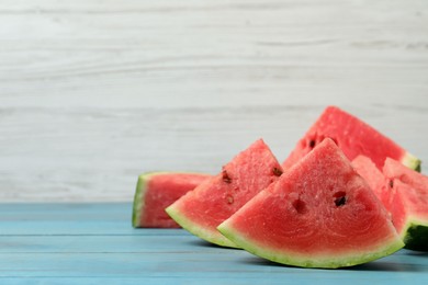 Photo of Slices of tasty ripe watermelon on turquoise wooden table, space for text