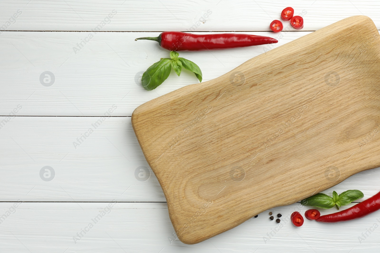 Photo of Cutting board and different spices on white wooden table, flat lay. Space for text