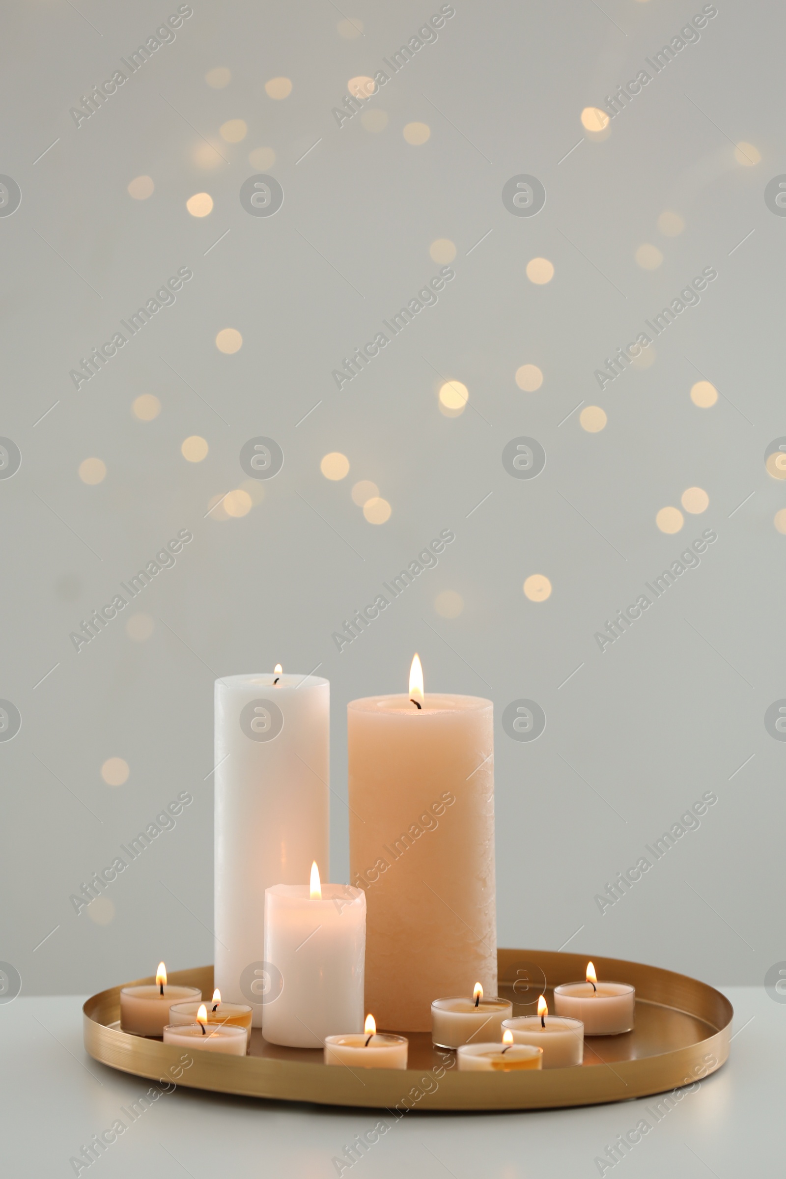 Photo of Many candles on table against blurred background with bokeh effect. Space for text