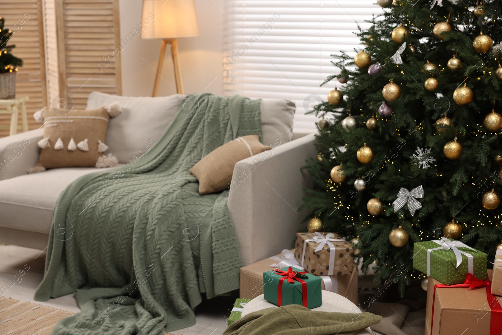 Photo of Sofa near Christmas tree in room. Festive interior design