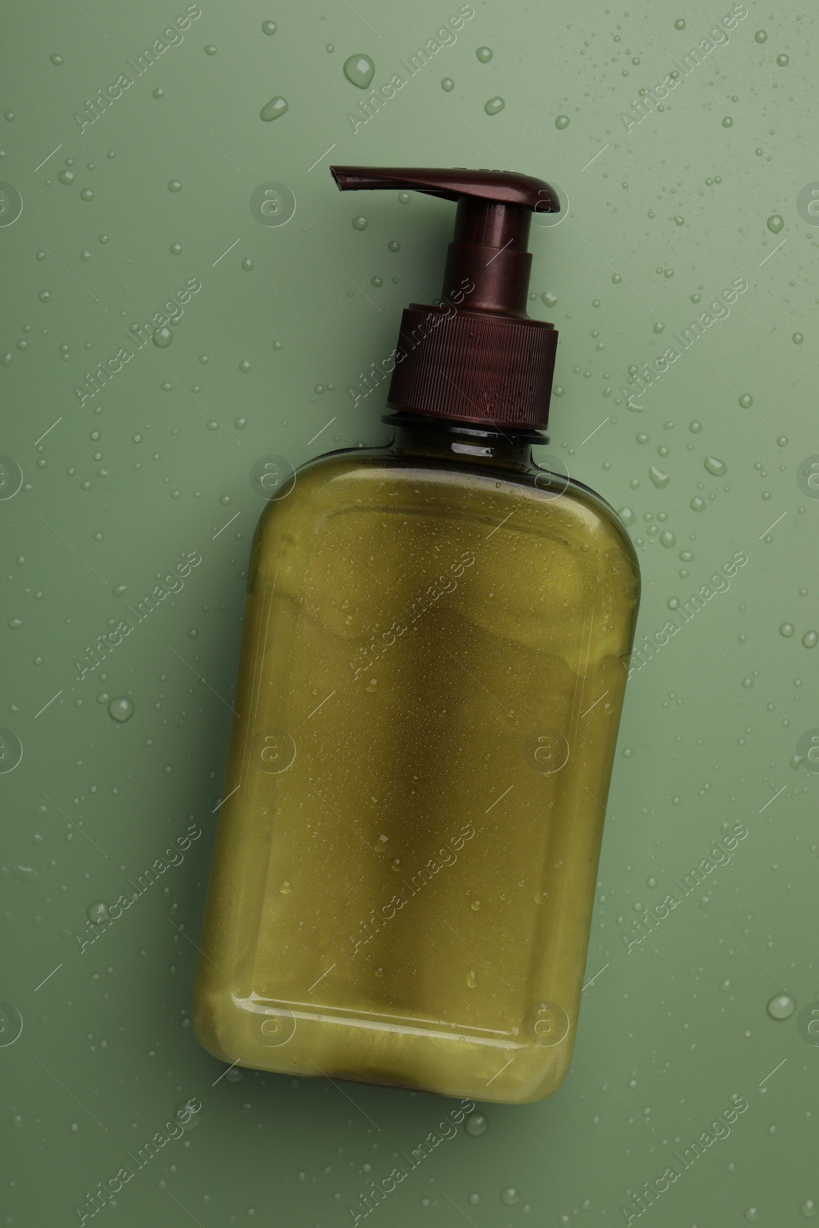 Photo of Bottle of face cleansing product on green background, top view