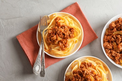 Plates with delicious pasta bolognese on grey background, top view