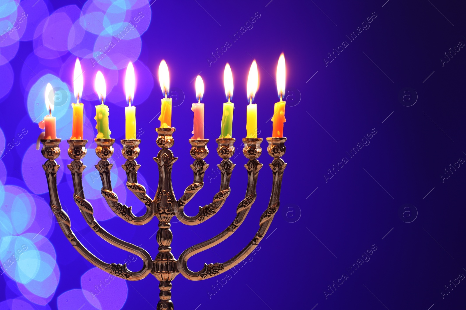 Photo of Hanukkah celebration. Menorah with burning candles on blue background with blurred lights, space for text