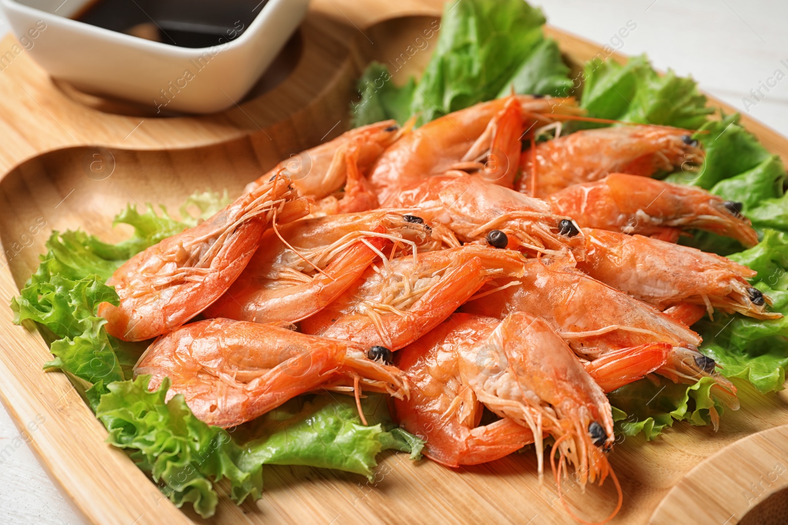 Photo of Wooden board with juicy shrimps, closeup