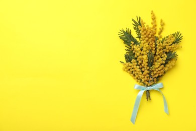 Beautiful mimosa bouquet on yellow background, top view. Space for text