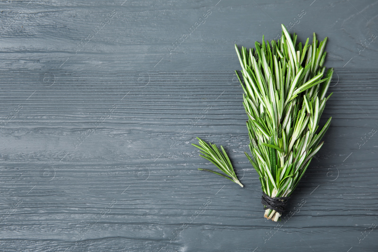 Photo of Bunch of fresh rosemary on color table, flat lay with space for text