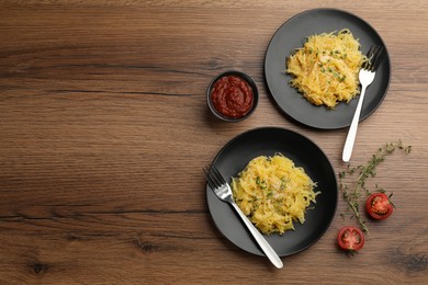 Photo of Tasty spaghetti squash with thyme and cheese served on wooden table, flat lay. Space for text