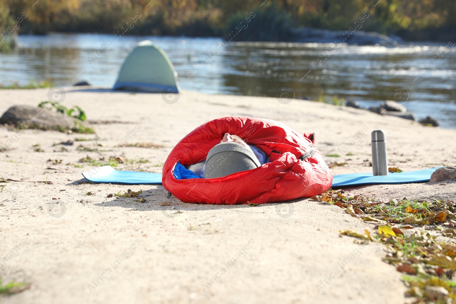 Photo of Male camper lying in sleeping bag on wild beach