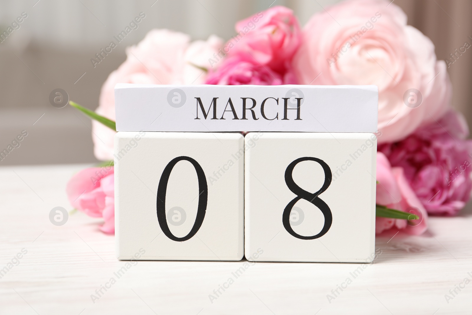 Photo of International Women's day - 8th of March. Block calendar and bouquet of beautiful flowers on white wooden table, closeup