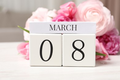 International Women's day - 8th of March. Block calendar and bouquet of beautiful flowers on white wooden table, closeup