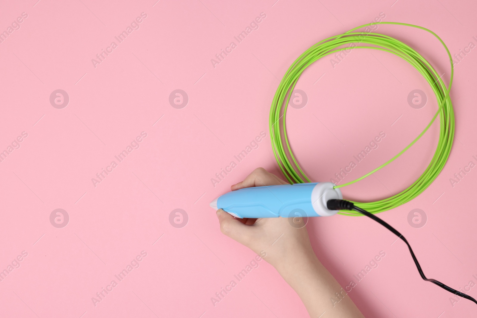 Photo of Boy drawing with stylish 3D pen on pink background, top view. Space for text