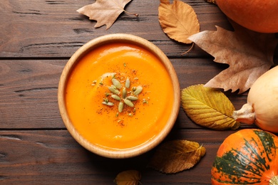 Flat lay composition with bowl of pumpkin soup on wooden background