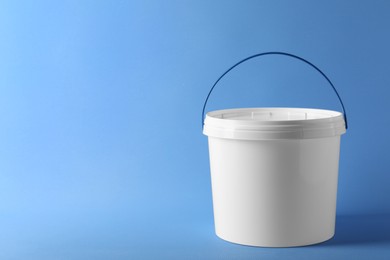 Photo of One plastic bucket with lid on light blue background. Space for text