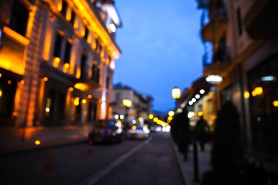 Blurred view of beautiful cityscape with glowing streetlights and illuminated building in evening