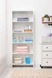 Shelving unit with stacked clean towels and toiletries in room