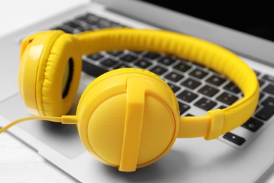 Photo of Stylish headphones on laptop, closeup. Modern technology