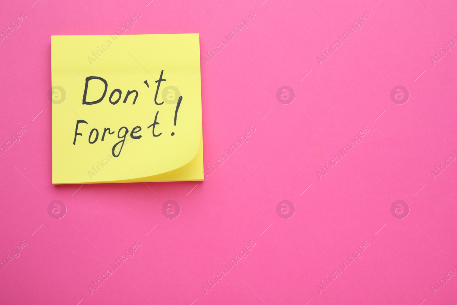 Photo of Paper note with phrase Don't Forget on pink background, top view. Space for text