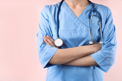 Photo of Doctor with stethoscope on pink background, closeup. Medical service