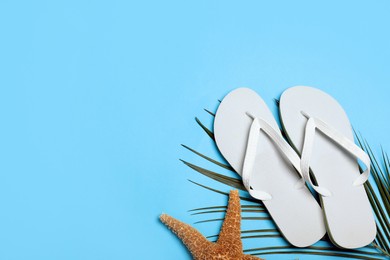 Photo of Stylish flip flops and starfish on light blue background, flat lay. Space for text