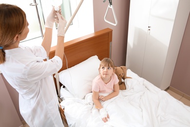 Doctor adjusting intravenous drip for little child in hospital