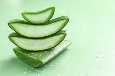 Fresh aloe vera pieces on green background, closeup. Space for text