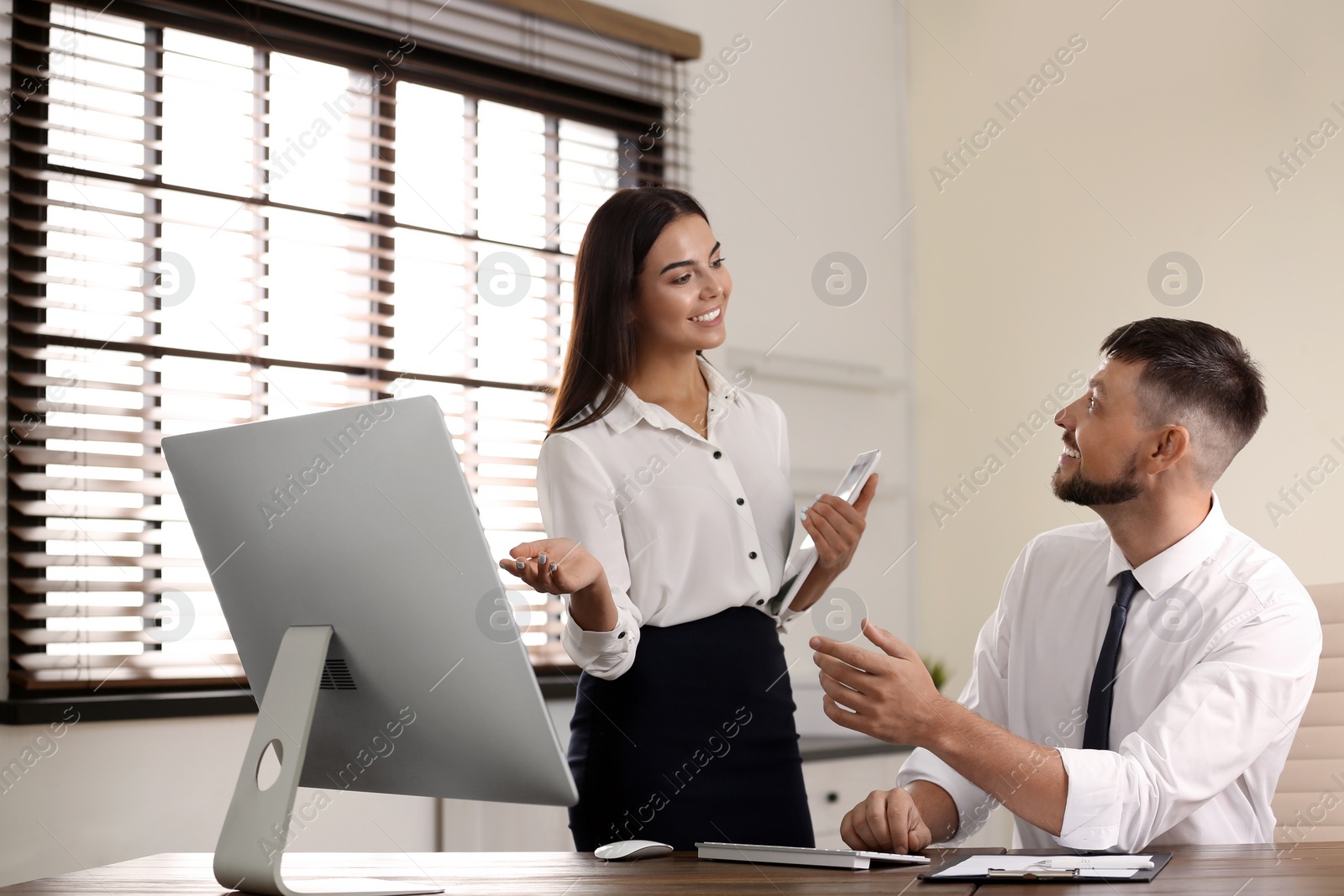 Photo of Woman helping her colleague with work in office