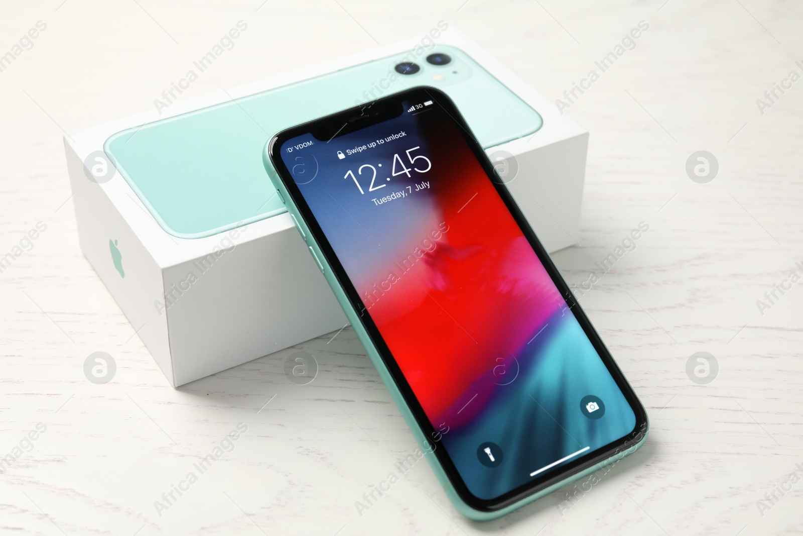 Photo of MYKOLAIV, UKRAINE - JULY 10, 2020: New modern Iphone 11 with lock screen and original box on white wooden table