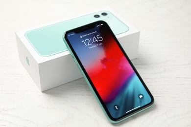 MYKOLAIV, UKRAINE - JULY 10, 2020: New modern Iphone 11 with lock screen and original box on white wooden table