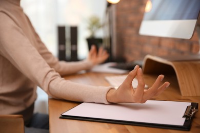 Photo of Woman meditating at workplace in office, closeup