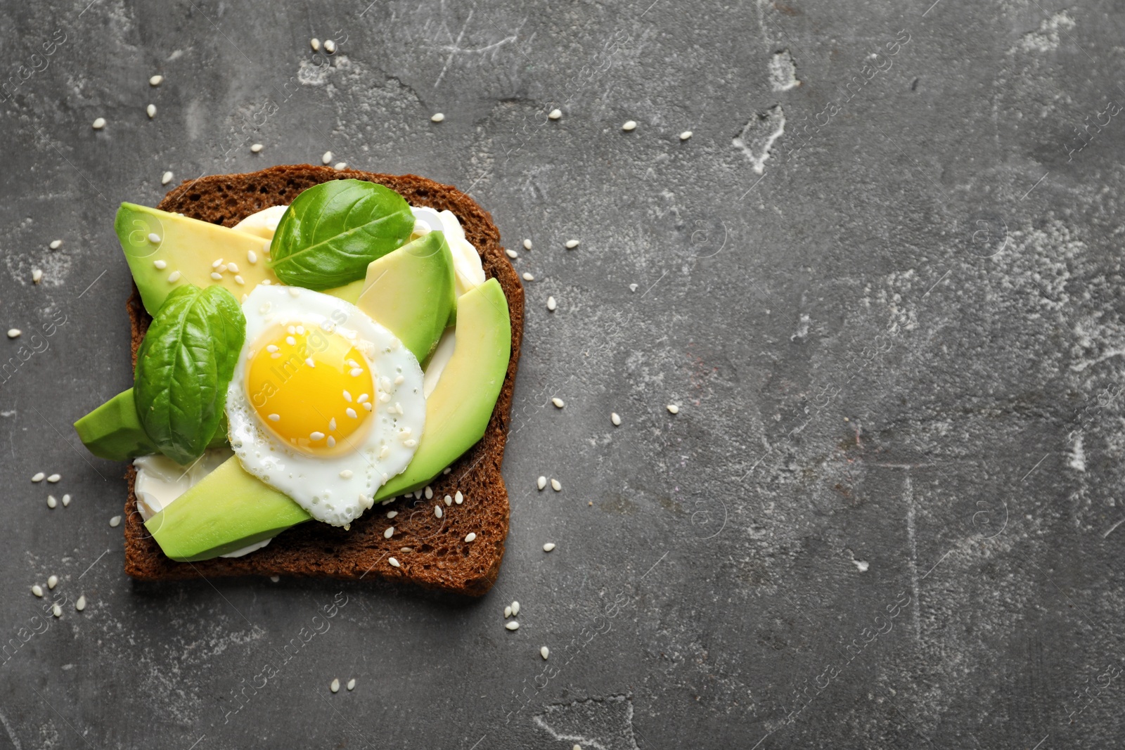 Photo of Toast bread with cream cheese, avocado and fried egg on dark background