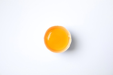 Photo of Cracked chicken egg with yolk on white background, top view