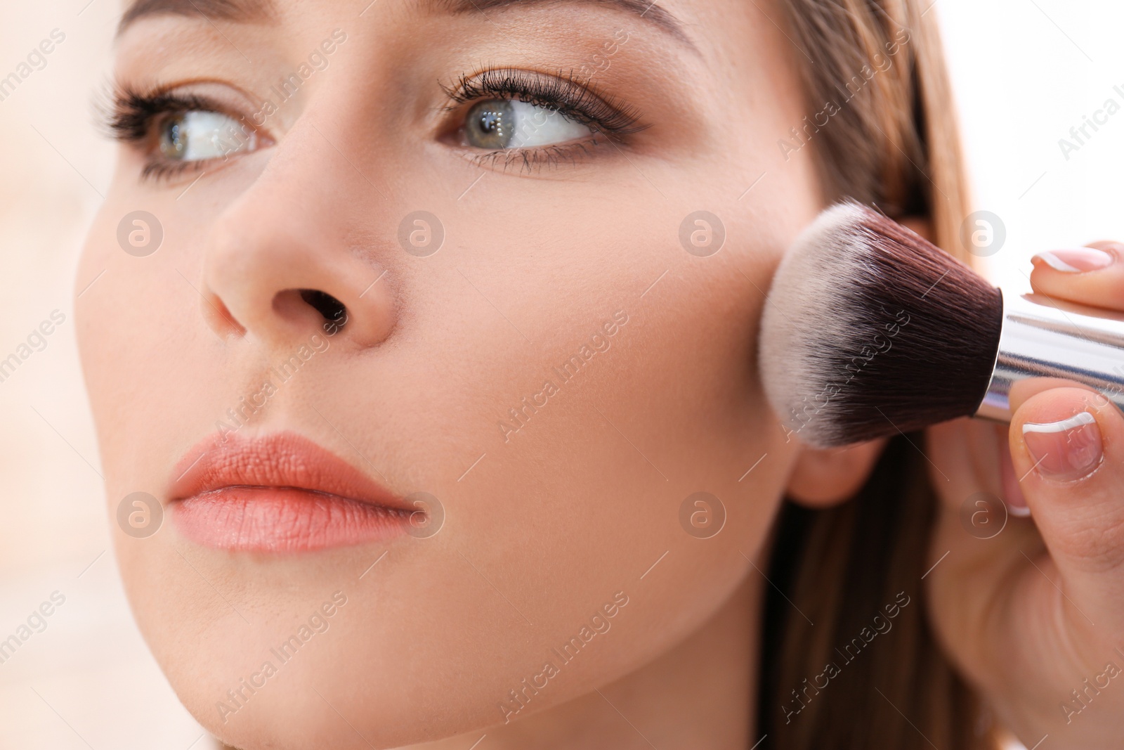 Photo of Professional visage artist applying makeup on woman's face in salon, closeup