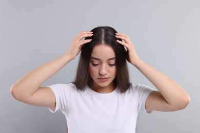 Photo of Woman suffering from dandruff problem on grey background