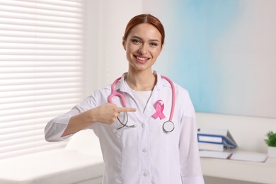 Photo of Mammologist pointing at pink ribbon in hospital. Breast cancer awareness