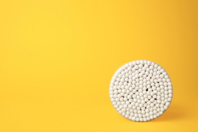 Photo of Container with new cotton buds on yellow background. Space for text