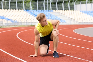 Photo of Man in sportswear suffering from knee pain at stadium