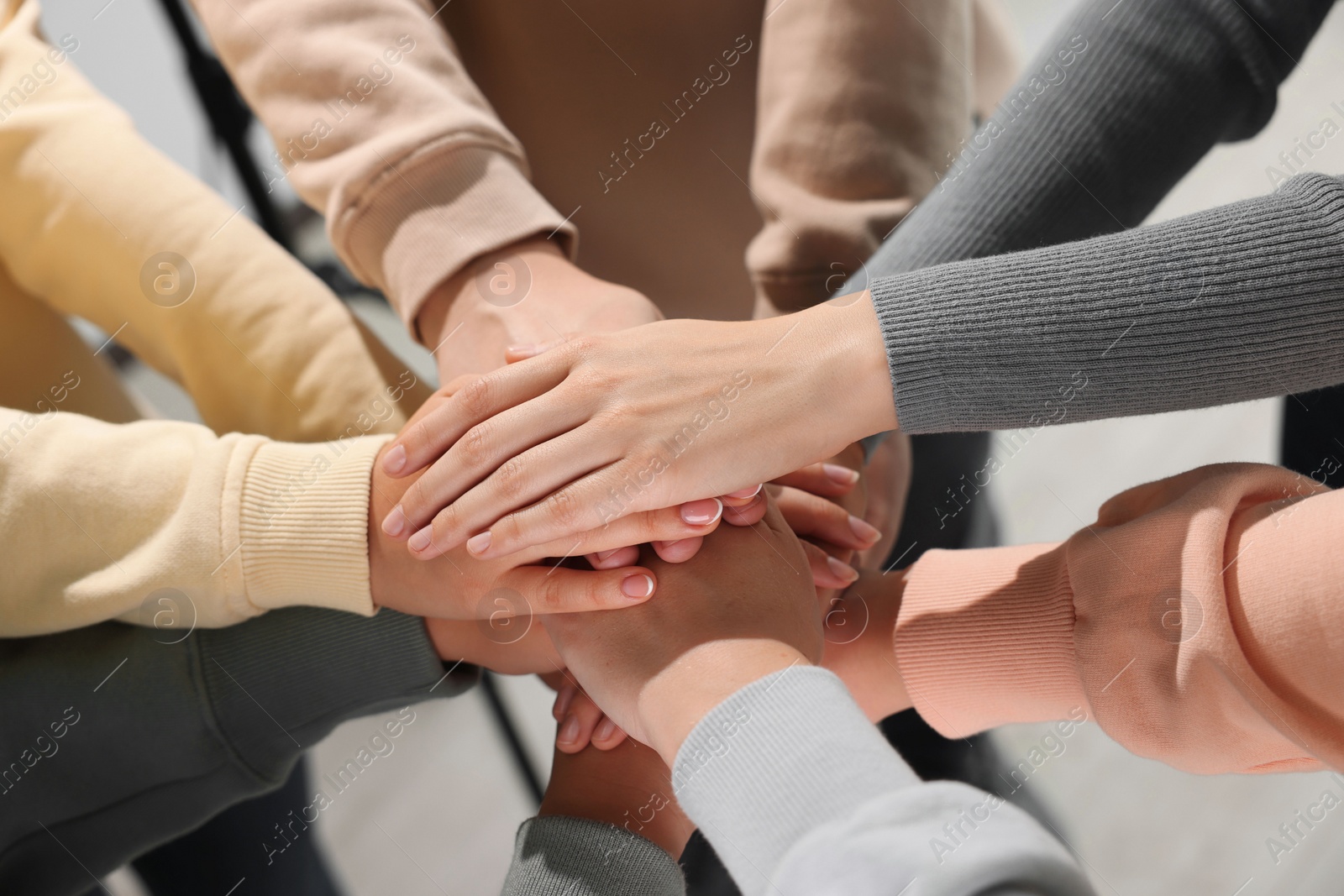 Photo of Group of people holding hands together indoors, closeup. Unity concept