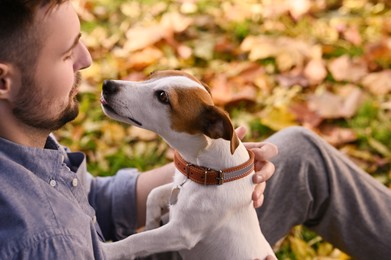 Man with adorable Jack Russell Terrier in autumn park, closeup. Dog walking